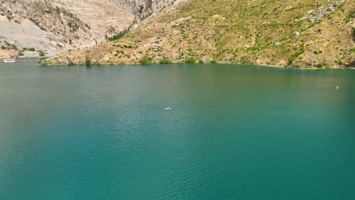 Aerial View Scenic Paddleboarding Journey Through a Lush Green Canyon Surrounded By Nature