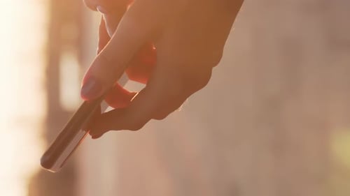 Woman's Hand Tapping Phone Screen in Golden Light