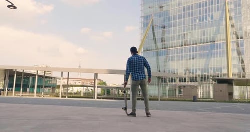 Portrait a boy practices skateboarding in the middle of the city, between buildings and skyscraper
