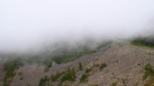Wide shot of fast cloudscapes covering hiking trails in rural landscape on top of mountain.