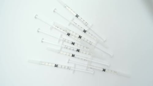 Multiple medical syringes falling on a white background