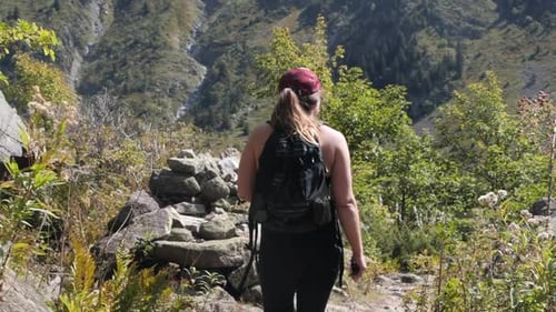 Stunning tracking shot of an attractive Caucasian woman on a mountain hike on a sunny day