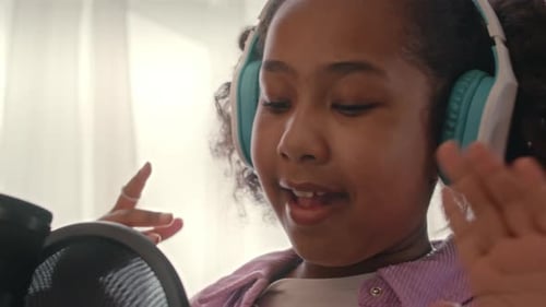 Young Girl Singing into Microphone with Headphones On