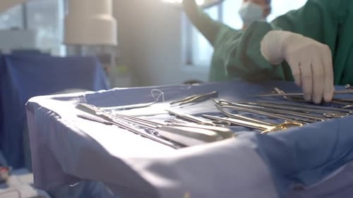 Midsection of female surgeon preparing surgical instruments in operating theatre, slow motion
