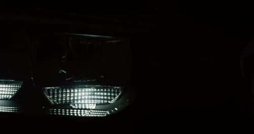 Close up of details of switched on headlights of anonymous prestigious luxury modern car. Shot in