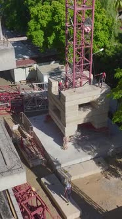 Vista aérea vertical de vídeo de una grúa torre construida por trabajadores cualificados en una construcción grande