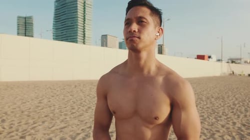 Young athletic man standing on the beach doing a warm up