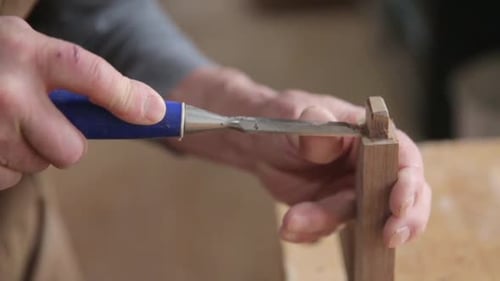 Carpenter carefully chiseling wooden furniture foot in calgary alberta Canada