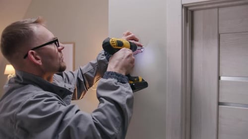 Man Screws Security Camera Mount Into Wall