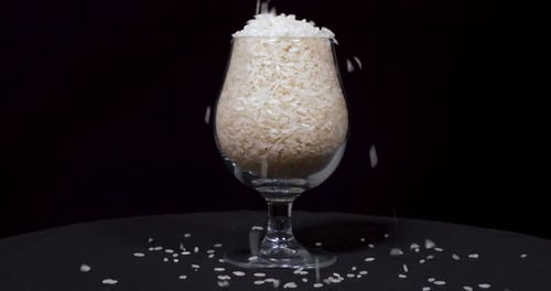 Rice Pouring Into Glass on Black Background