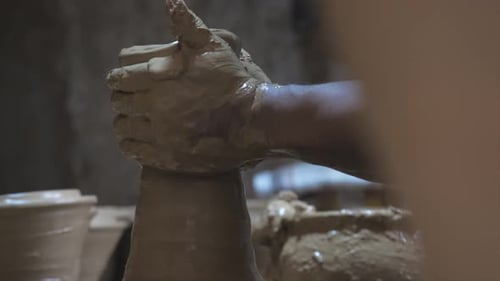 Side view of potter shaping the clay vessel rotating on the potters wheel.