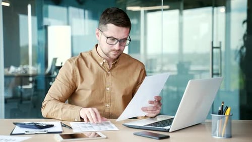 Happy financier satisfied with financial results sitting at the workplace in business office.