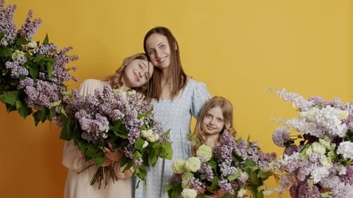 Happy Mother and Daughters with Flowers in Studio