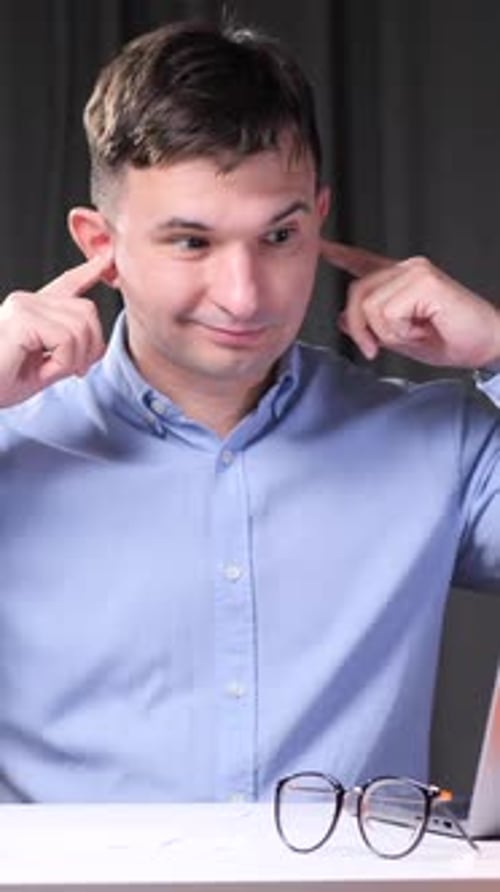 Vertical Video Office Worker Plugging Ears at Desk with Stack of Documents