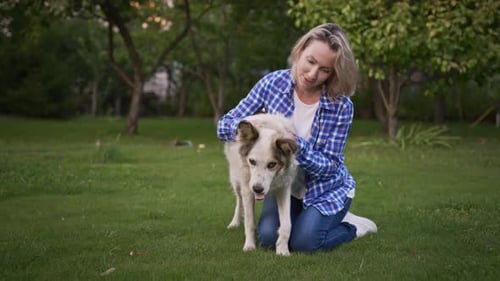 Young Woman in the Garden with Her Dog The Owner Loves Her Pet and is Happy to Spend Time with Him