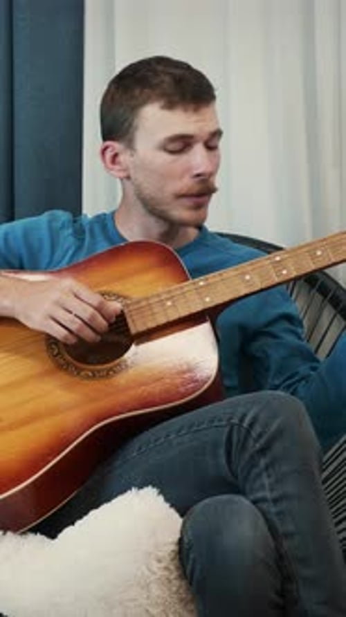 Man Playing Acoustic Guitar Sitting in Chair Indoors