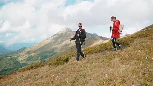 Couple Hikers Man and Woman Go Down Mountain Hiking with Sticks in Hands