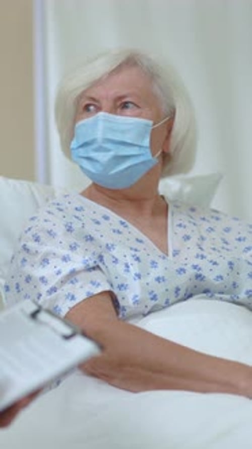 Young Doctor Giving Consultation Visiting Senior Unhealthy Woman Recovering Illness in Hospital Room