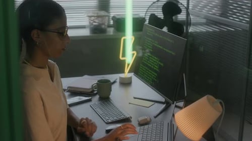 Junge IT-Spezialistin, die nachts im modernen Büro mit Programmcodierung arbeitet