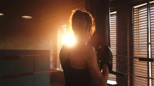 Woman Boxing on a Punching Bag at Sunrise