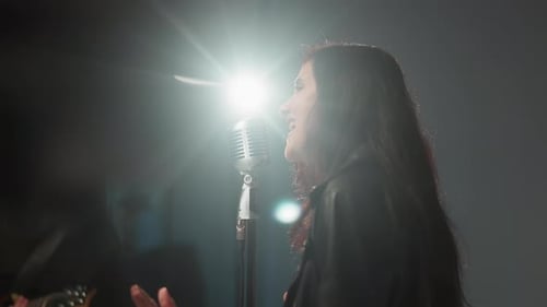 Woman Sings Passionately into Microphone on Stage