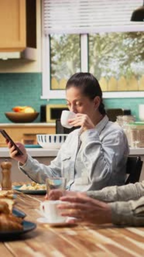 Vidéo verticale Famille avec une préadolescente servant le petit déjeuner ensemble dans une cuisine lumineuse