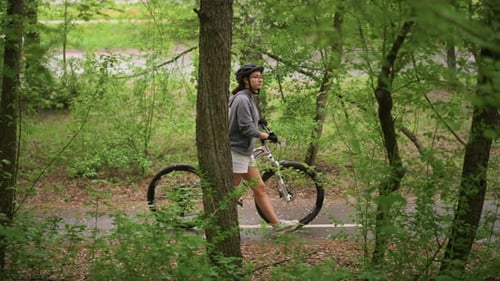 Woman Leisurely Promenades With Bicycle Through Lush Forest Scenery Casual Female Rider Pauses