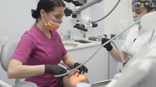 Zahnärztin mit ihrer Assistentin mit Handschuhen an den Händen und Masken am Mund bereitet männlichen Pati vor
