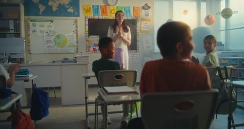 Female Teacher Introducing New Young Pupil in Front of Class Full of Primary School Students