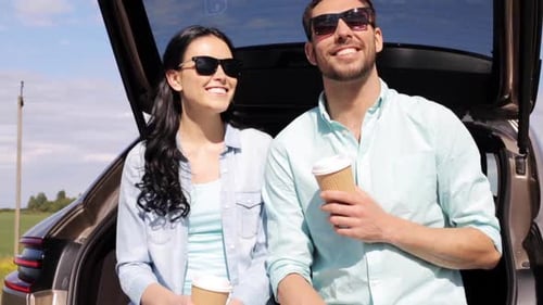 Happy young couple on summer road trip enjoying coffee outdoors in the country