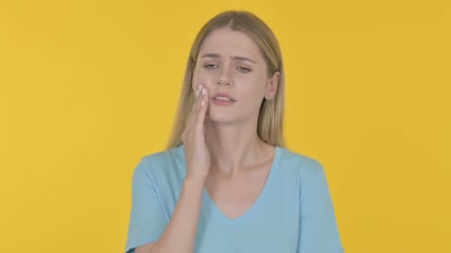 Young Woman having Toothache on Yellow Background