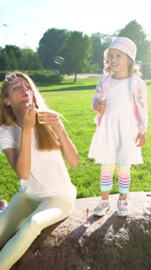 Mother and Daughter Blowing Bubbles at Park