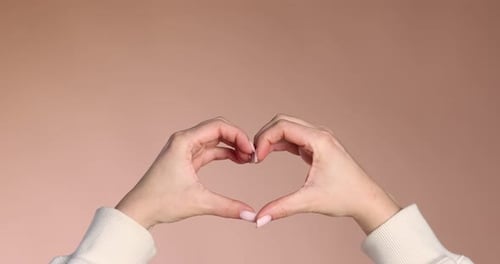 Hand Gesture Makes Heart Shape on Neutral Background