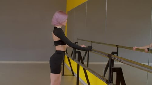 Woman Stretching at Ballet Barre in Modern Studio