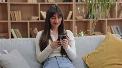Woman Using Smartphone on Sofa in Home