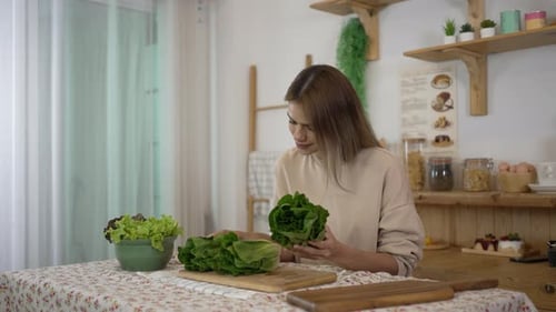 Woman Examining Lettuce in Bright Home Kitchen