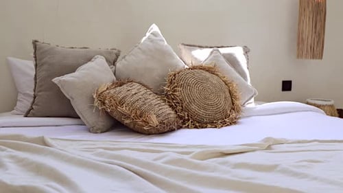 Lots of throw pillows on a bed in Bali boho villa bedroom, close-up