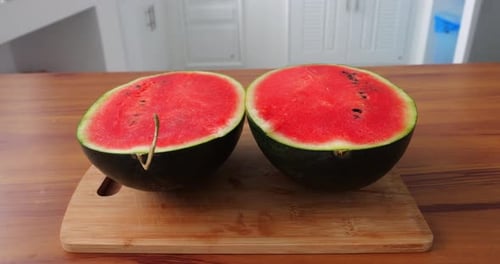 Rotierende Schussansicht einer reifen und saftigen Bio-Wassermelone von oben, geteilt in zwei Hälften auf einem