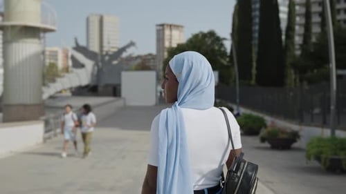 Junge lässige afrikanische muslimische Frau mit Hijab, die durch die Stadt geht
