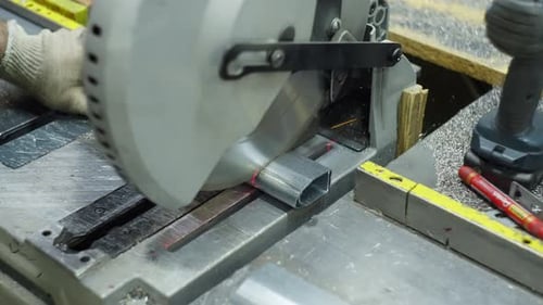 Engineer Using Industrial Saw to Cut Metal Profiles in a Factory Workshop