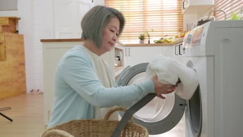 Mature Woman Loading Washing Machine at Home