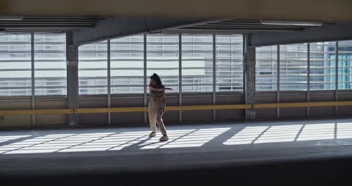 Jovem mulher dançando em um prédio de estacionamento vazio