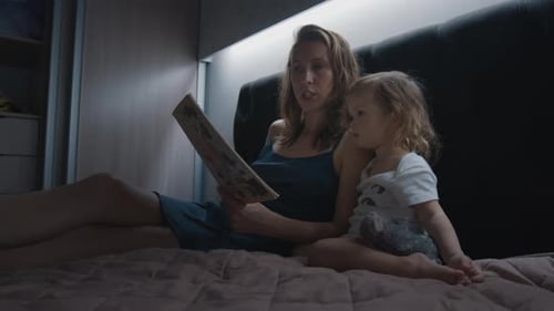Mother and Child Reading a Book on Bed