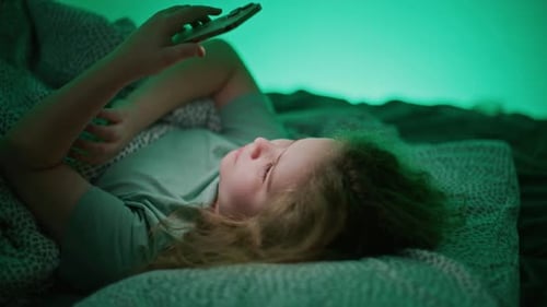 Girl Lies in Bed Using Smartphone at Night