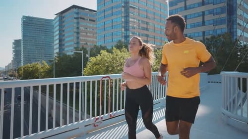 Man and Woman Jogging Together Across a Bridge