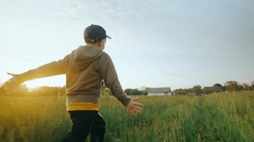A Little Boy Runs Straight Along the Path Through the Green Grass