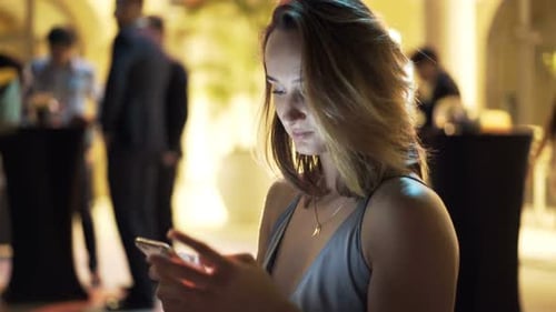 Pretty Woman Texting On Smartphone And Drinking Wine On Sitting In Cafe At Night