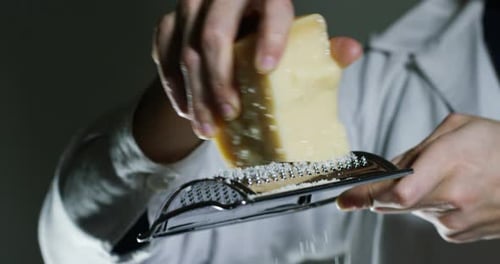 Slow motion of A cook grater Parmesan cheese, typical Italian cheese, on the plate just freshly br