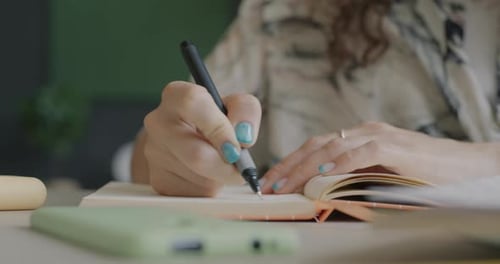 Woman Writes in Notebook at Desk