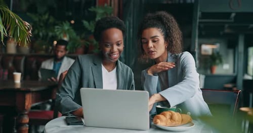 Women, laptop and meeting in coffee shop for business, startup management and budget planning